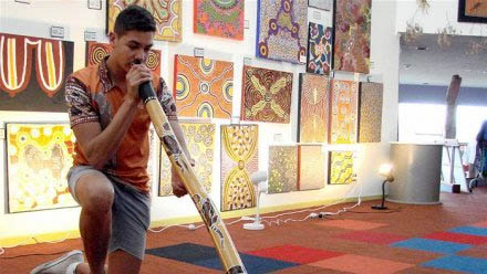 Matthew Joseph memainkan didgeridoo pada peluncuran Women's Business karya Anangu Tjutaku Tjukurpa di Burrunju Art Gallery. (Credit: ABC Licensed)