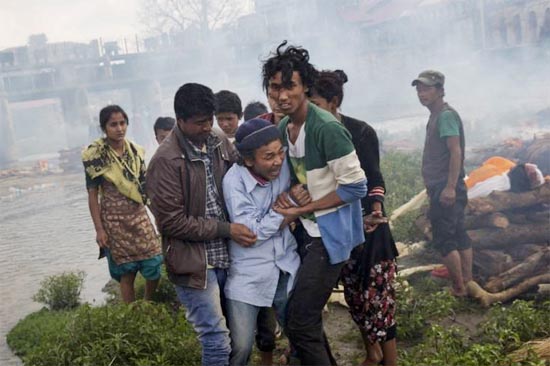 Warga tak kuasa menahan kesedihan saat kremasi massal di Kuil Pashupatinath, Sungai Bagmati di Kathmandu, Nepal, 26 April 2015. FOTO : AP PHOTO/BERNAT ARMANGUE