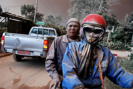 Warga dengan wajah tertutup abu naik sepeda motor ketika Gunung Sinabung meletus, di Desa Sukandebi, Kabupaten Karo, Provinsi Sumatera Utara (13/06/2015). FOTO : RONY MUHARRMAN/ANTARA