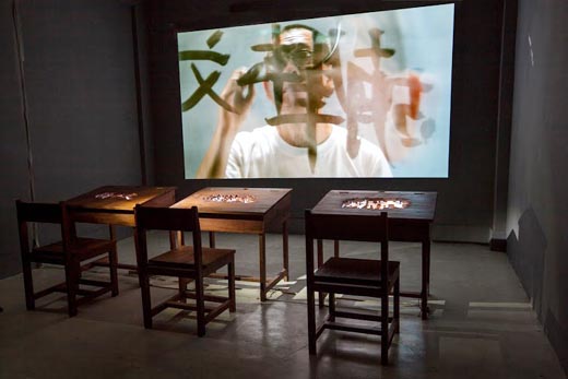 "Writing in the Rain", wooden chair and desk, 24" television, single channel video 6'  11" (looping), 2011. FOTO : FX HARSONO