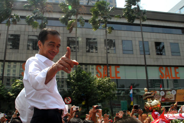 Jokowi tak henti hentinya melontarkan senyum dan menunjuk masyarakat yang mengelu-elukannya dalam arak-arakan menghantar Jokowi menuju Istana Negara. FOTO : Ahmad Fauzan Sazli