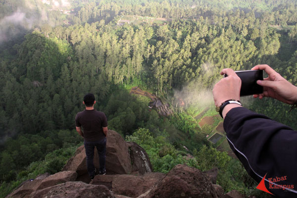 Seorang pengunjung berfoto menghadap ke bawah di bukit keraton atau yang dikenal dengan bukit instagram. FOTO : FAUZAN