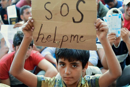 Salah seorang pengungsi asal Suriah di ibukota Hongaria, Budapest membawa plakat bertuliskan "SOS, tolonglah kami'.