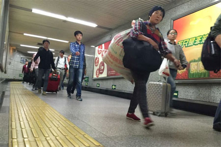 Para wisatawan di kereta bawah tanah Airport Express Beijing akan bepergian ke AS, Kanada, dan Hong Kong untuk menikmati masa libur nasional.